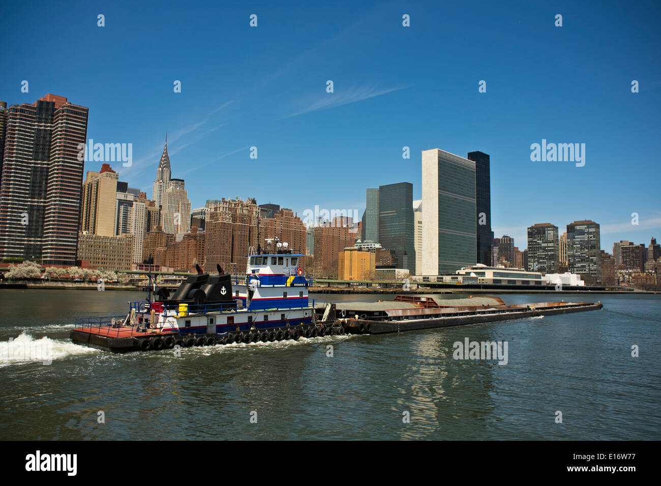Tugboat pushing barges de gravier sur New York City's East River, Chrysler Building et bâtiment de l'Organisation des Nations Unies en arrière-plan Banque D'Images