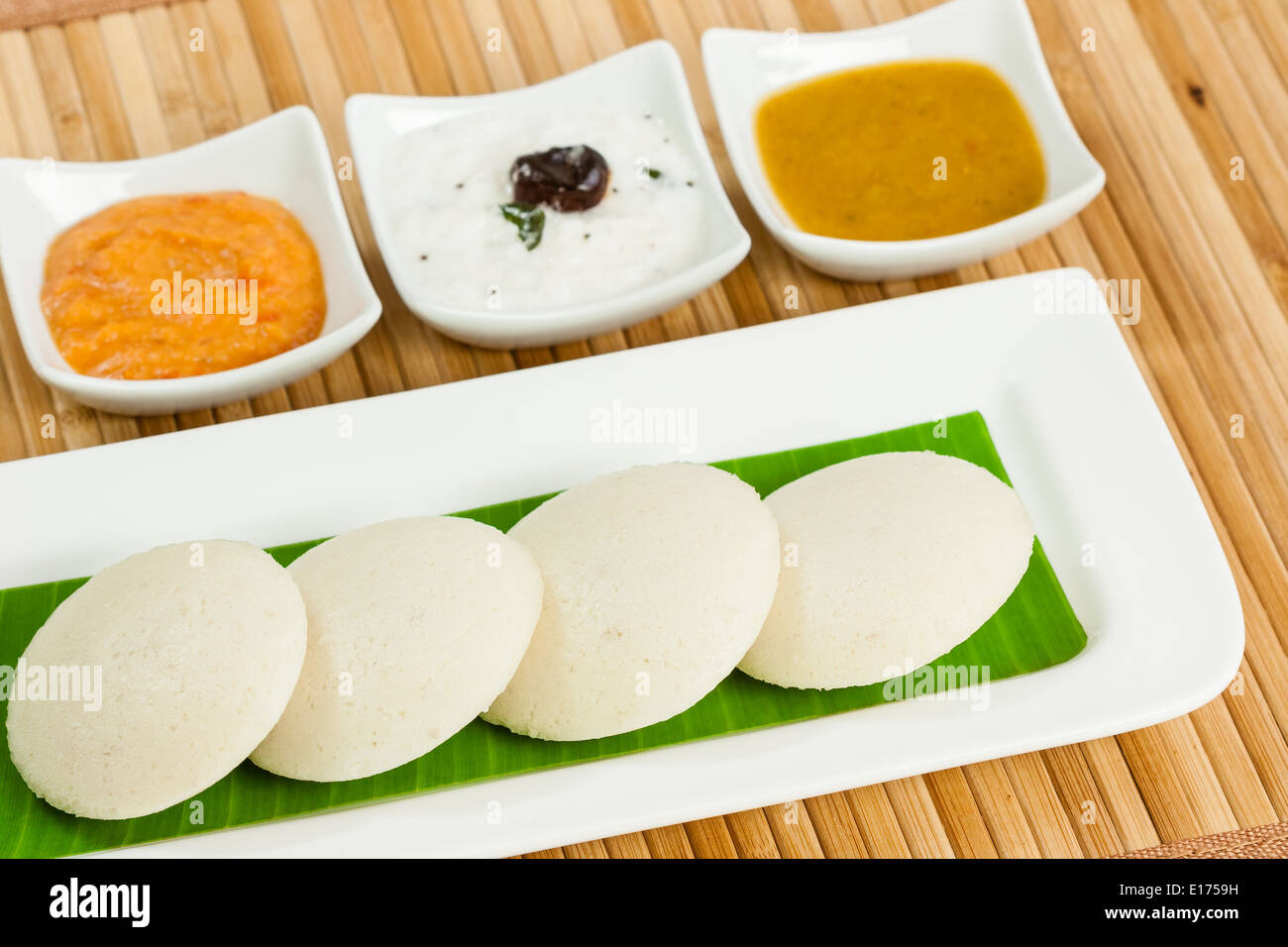 Le petit déjeuner traditionnel de l'Inde du sud sans rien faire (IDLI) servi avec des condiments (Chutney de tomates chutney de noix de coco, et des cochons) sur une plaque Banque D'Images