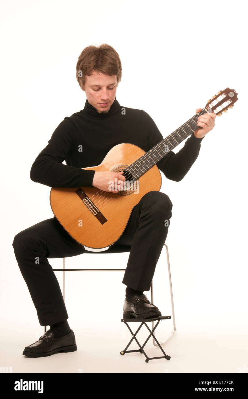 Guitariste classique mâle blanc montrant comment tenir une guitare strum et photographié contre fond blanc Banque D'Images
