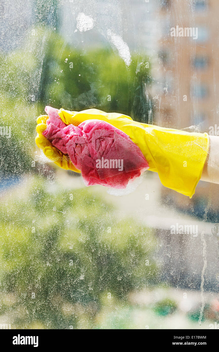 Gant en caoutchouc jaune en main lave-vitre par l'eau savonneuse Banque D'Images