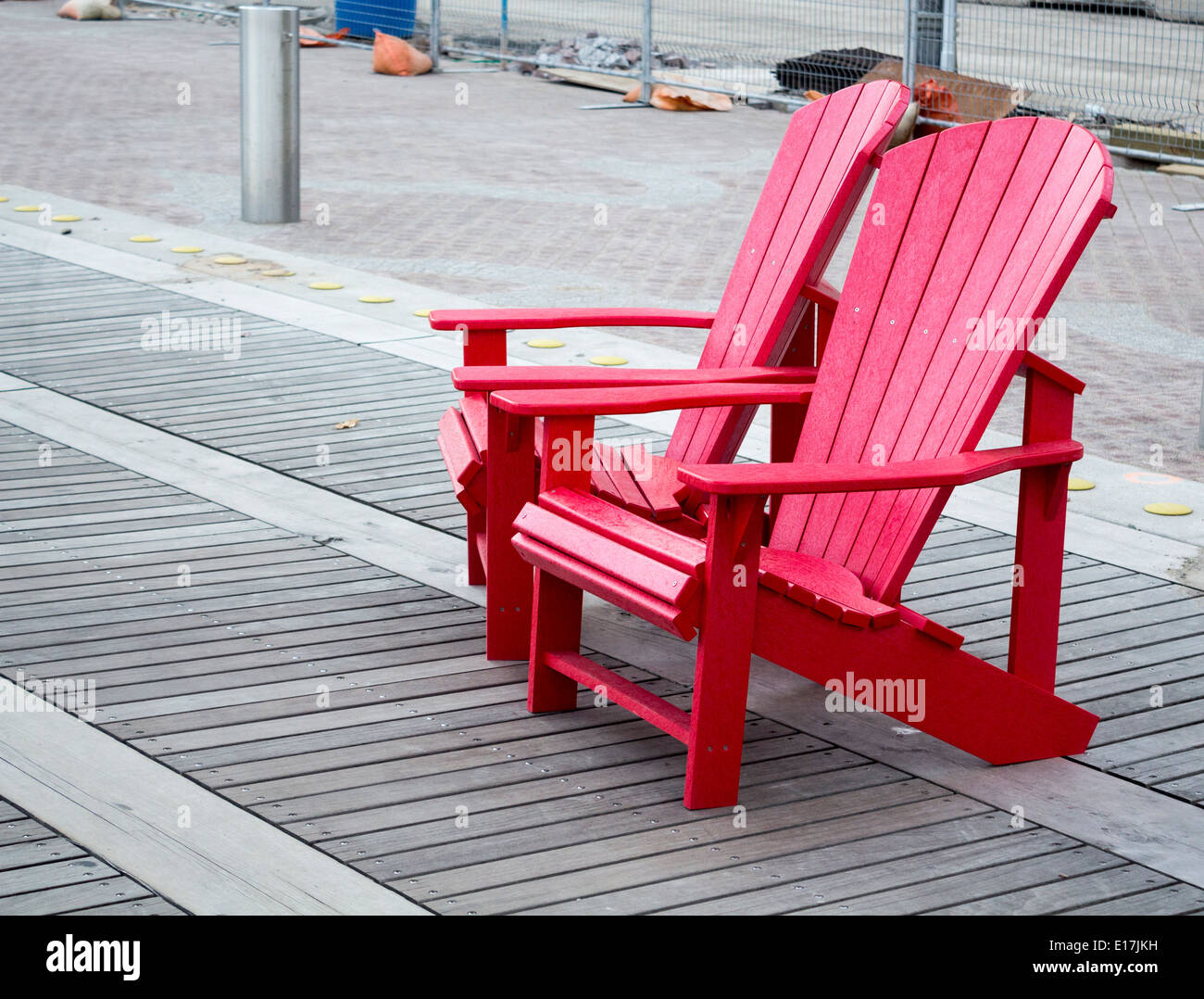 Deux chaises Adirondack rouge à la base de la plate-forme de l'onde sur Queens Quay, à Toronto. Banque D'Images