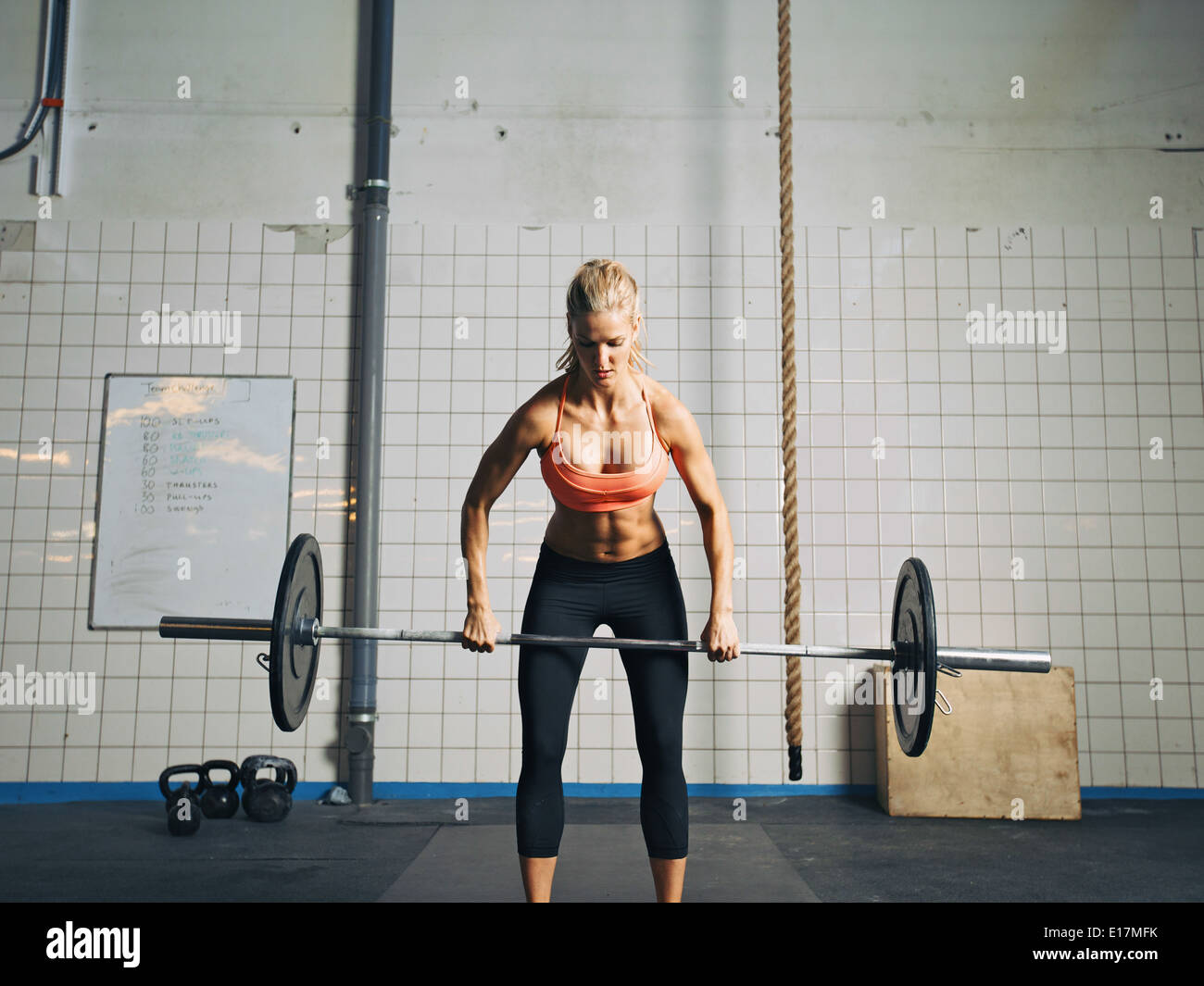 Mettre en place et attractive caucasian female tenant un barbell dans ses mains. Femme Crossfit poids lourds de levage en salle de sport. Banque D'Images