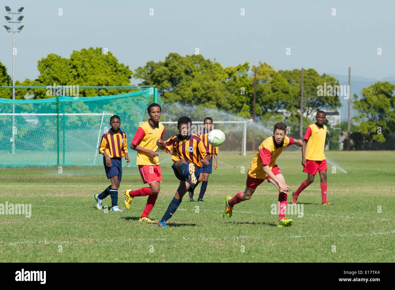 Un joueur de football junior lance la balle d'autres joueurs à la poursuite, Le Cap, Afrique du Sud Banque D'Images