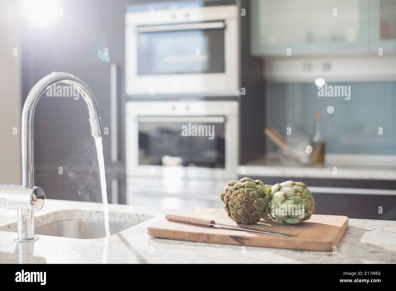 Les artichauts sur une planche à découper dans la cuisine domestique moderne Banque D'Images