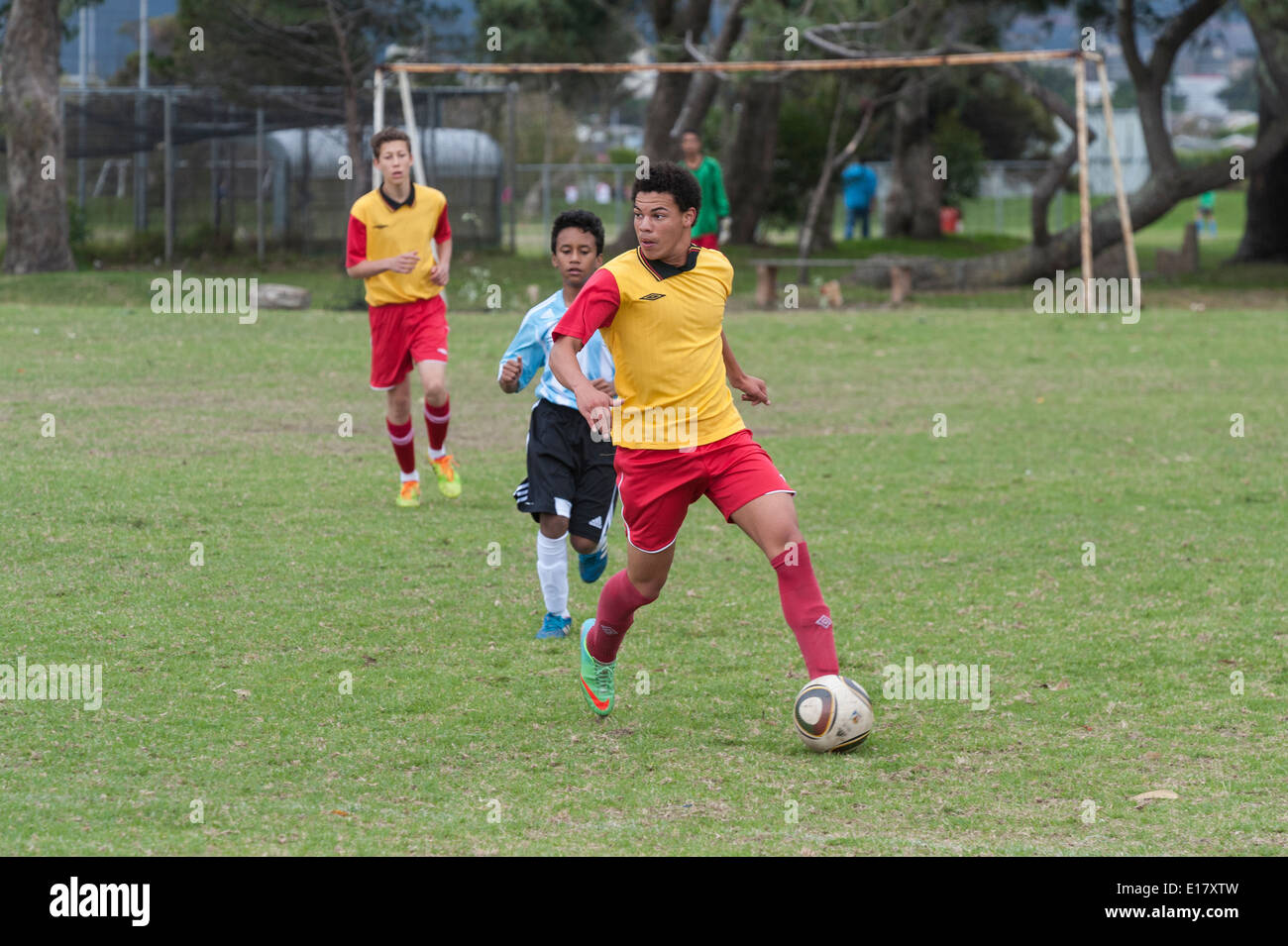 Un joueur de football junior exécutant avec la balle, à où à passer, Le Cap, Afrique du Sud Banque D'Images