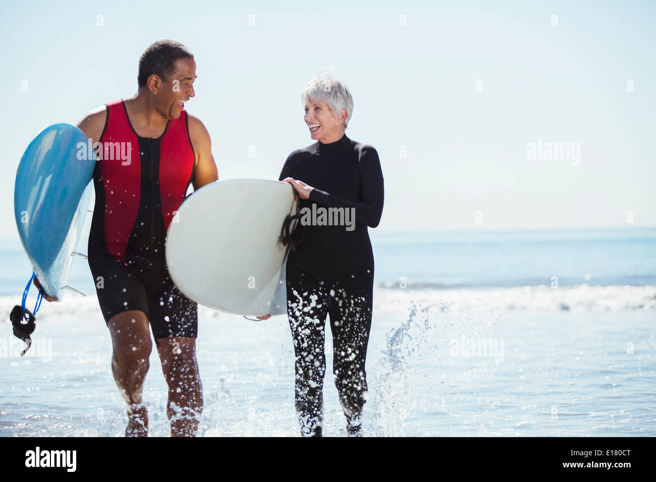 Senior couple with surfboards on beach Banque D'Images