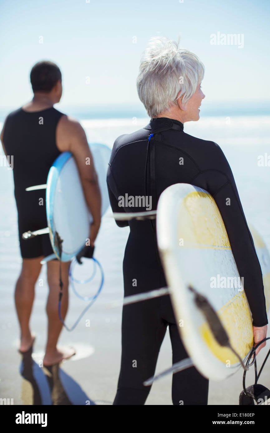 Senior couple with surfboards on beach Banque D'Images