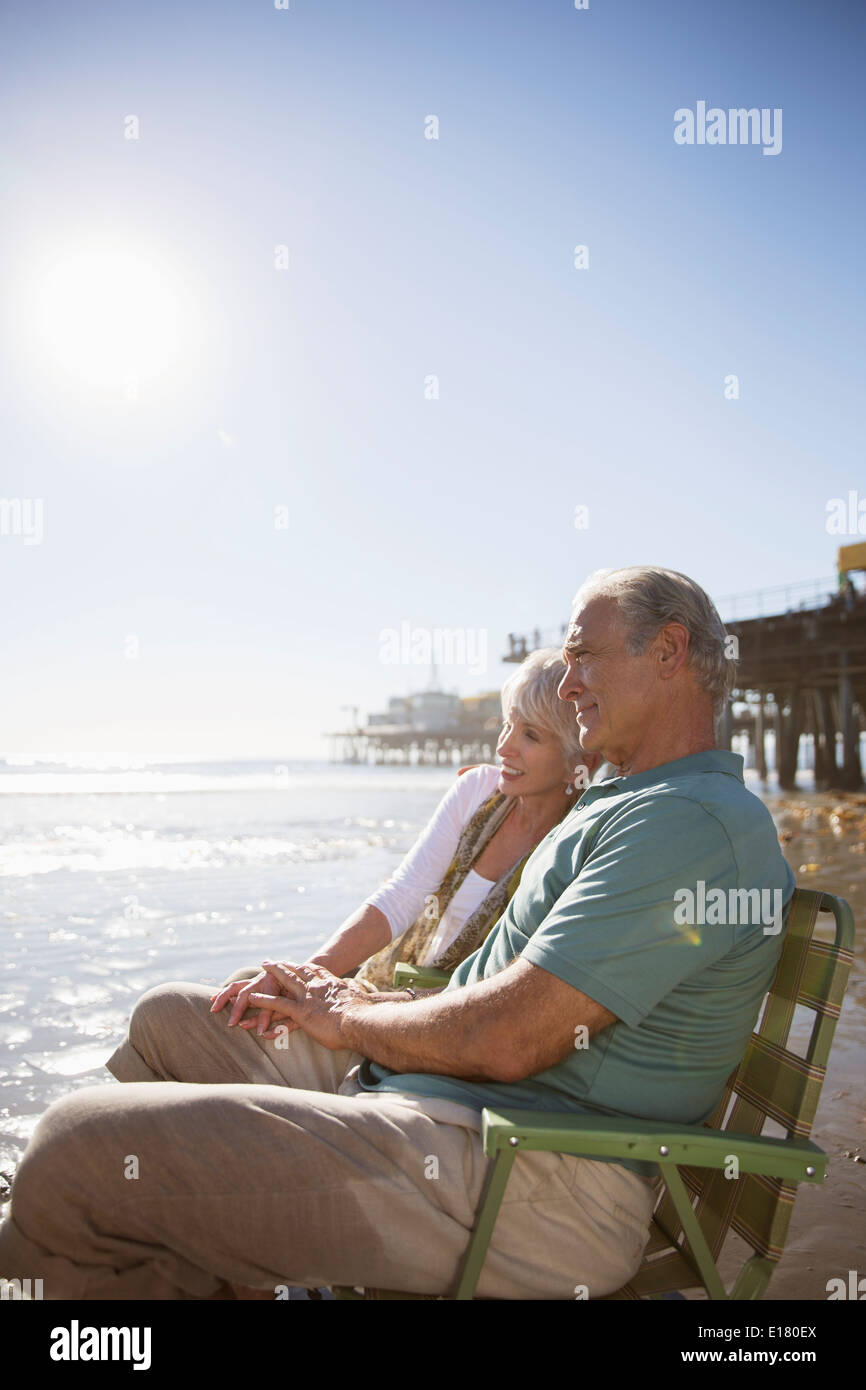 Senior couple relaxing in lawn chairs on beach Banque D'Images