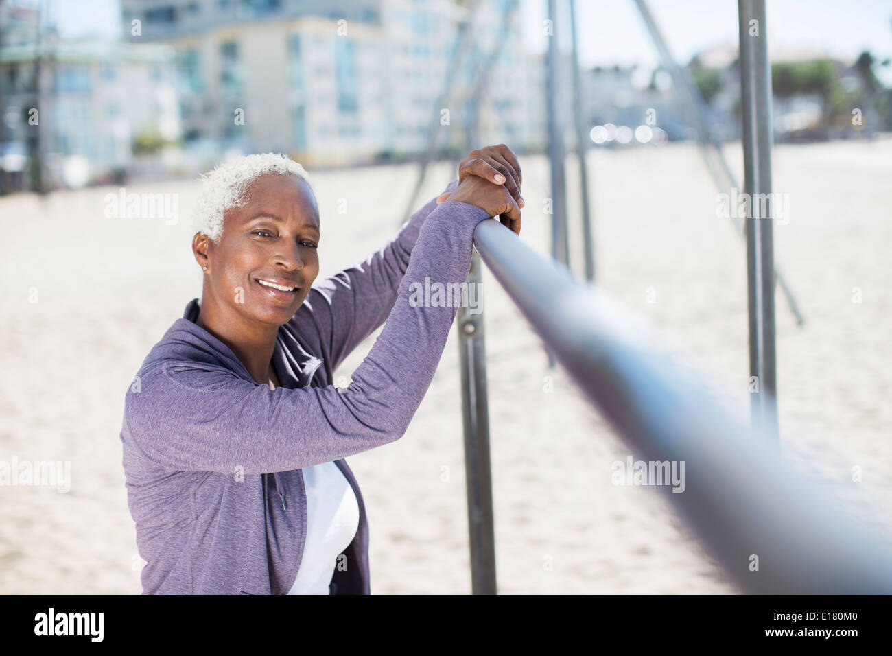 Portrait of smiling woman leaning on bar à l'aire de jeux sur la plage Banque D'Images