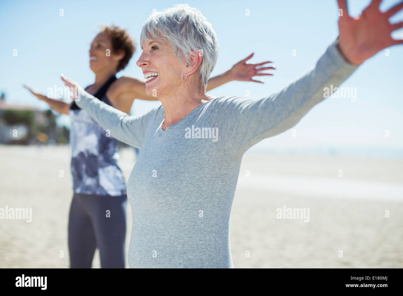 Les femmes âgées stretching arms on beach Banque D'Images