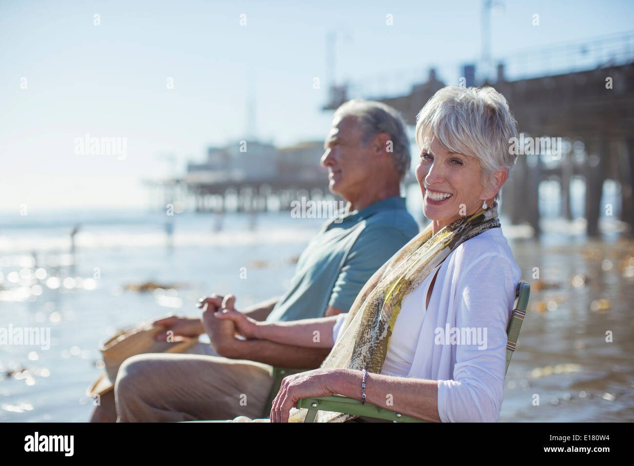 Portrait of senior couple relaxing in lawn chairs on beach Banque D'Images