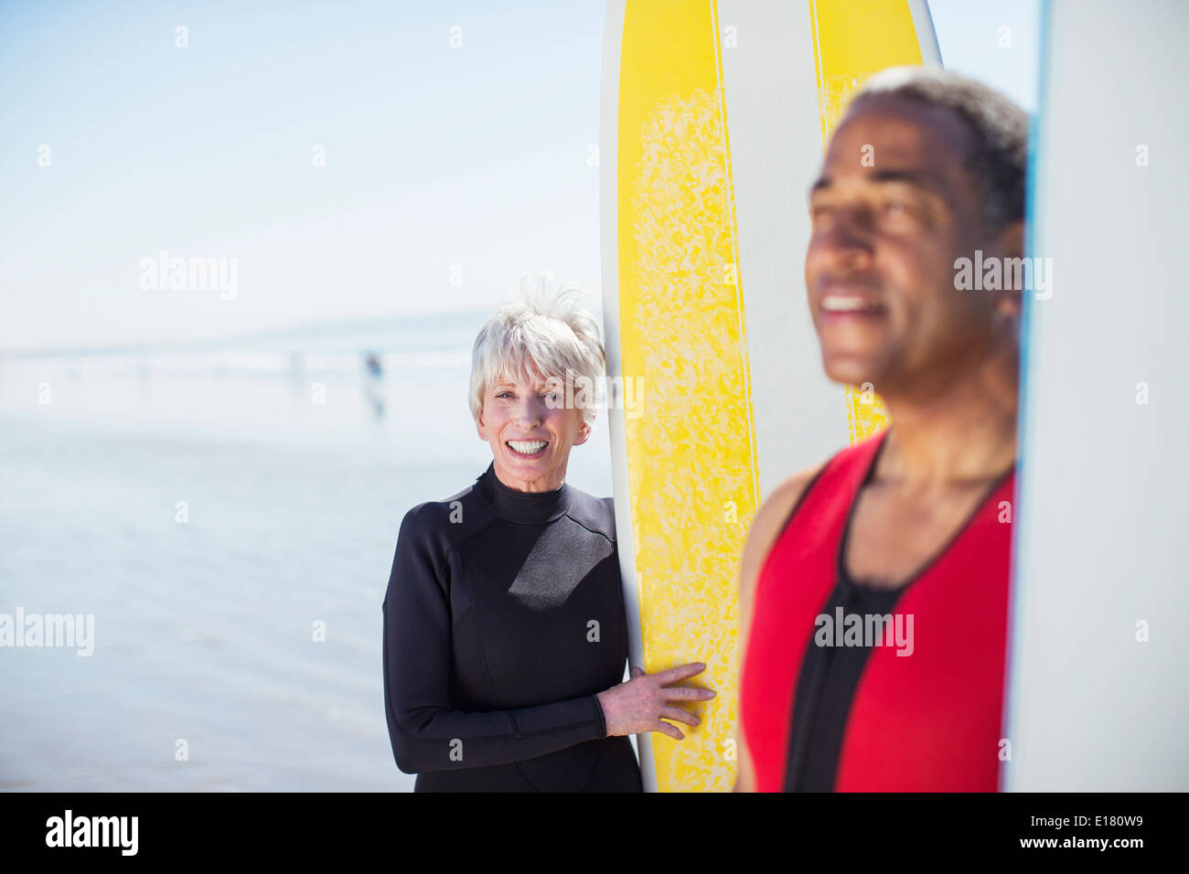 Portrait of senior couple with surfboards on beach Banque D'Images