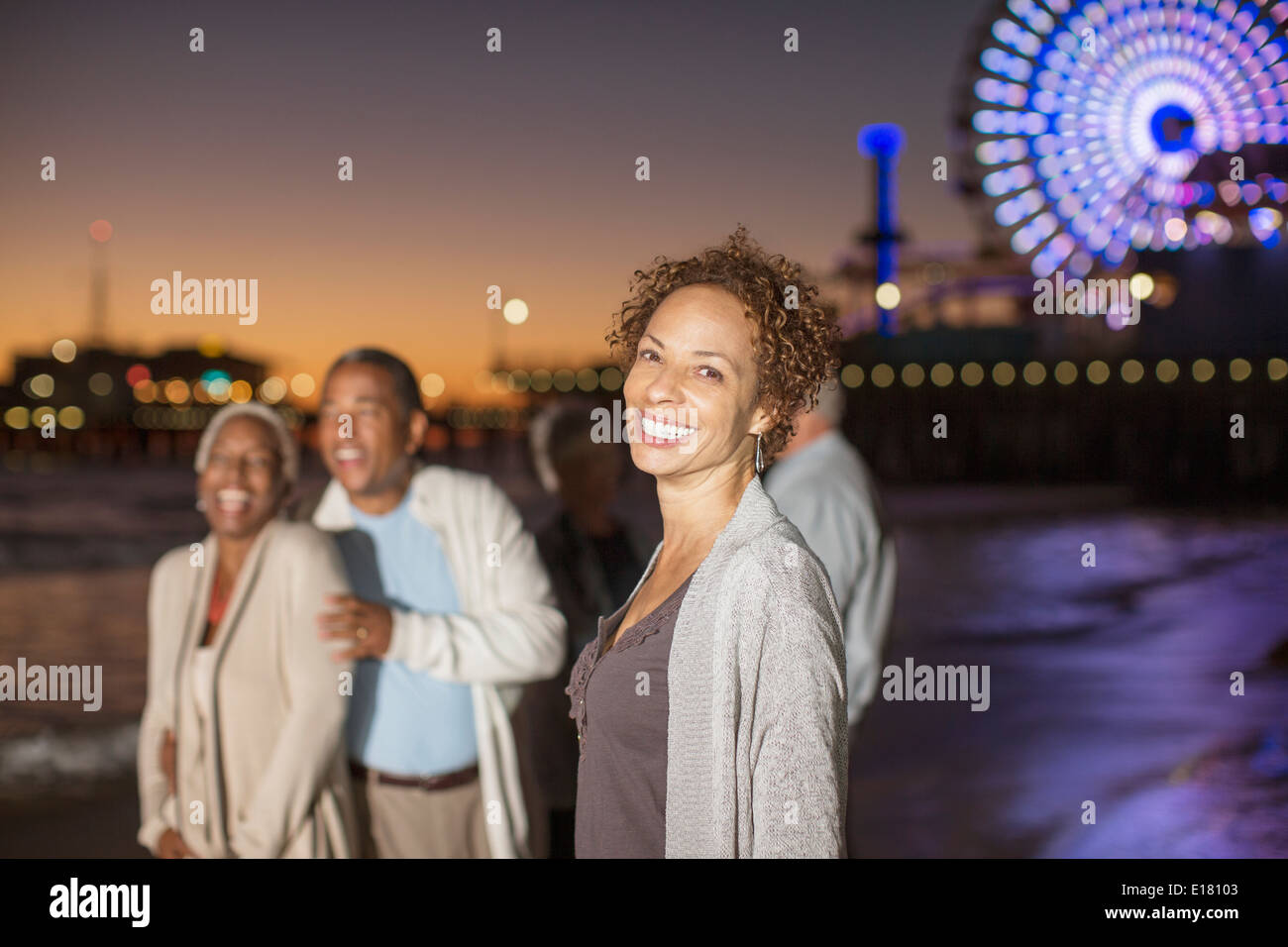 Portrait of smiling woman on beach avec des amis dans la nuit Banque D'Images