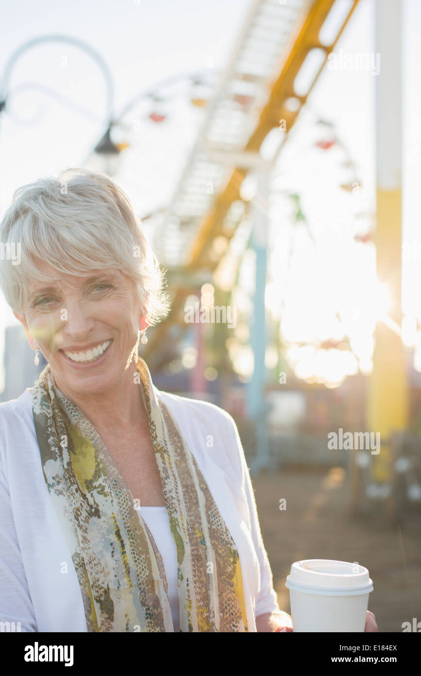 Portrait of smiling senior woman drinking coffee at amusement park Banque D'Images
