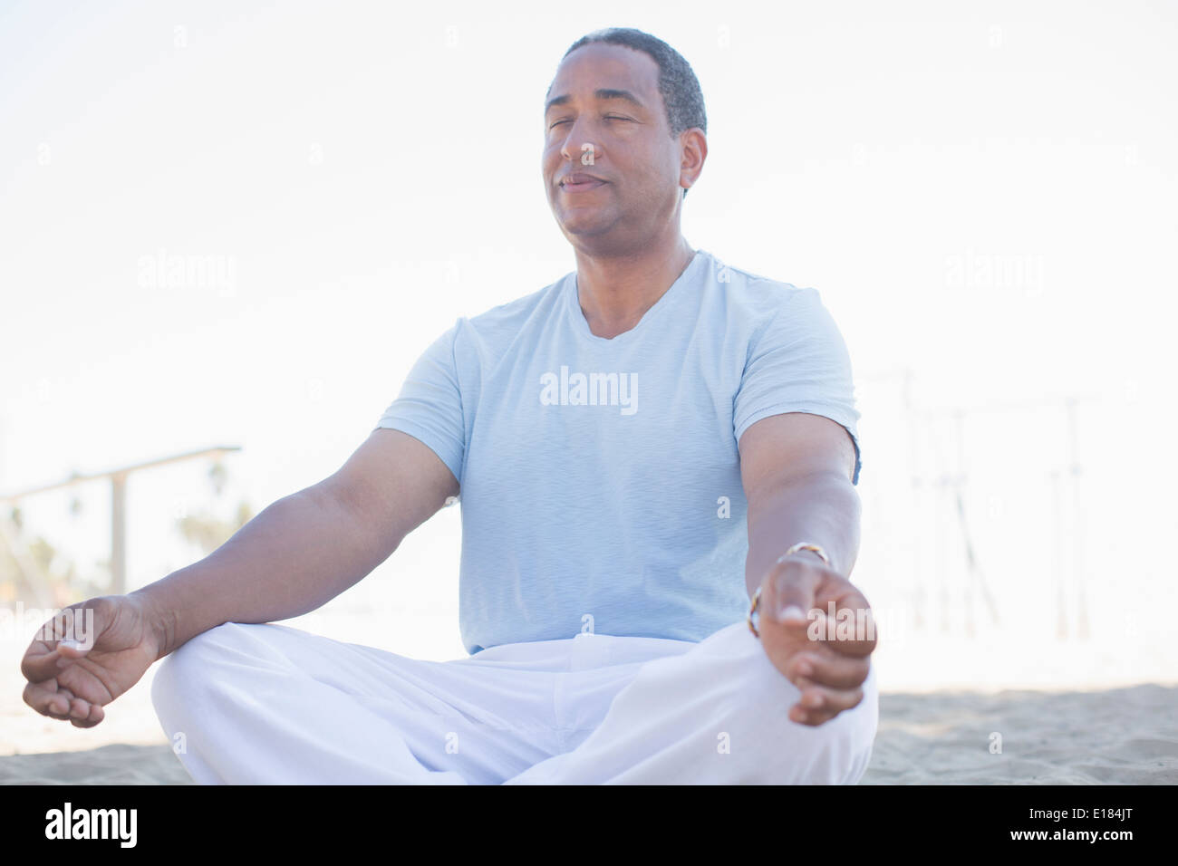 Serene woman meditating in lotus position on beach Banque D'Images