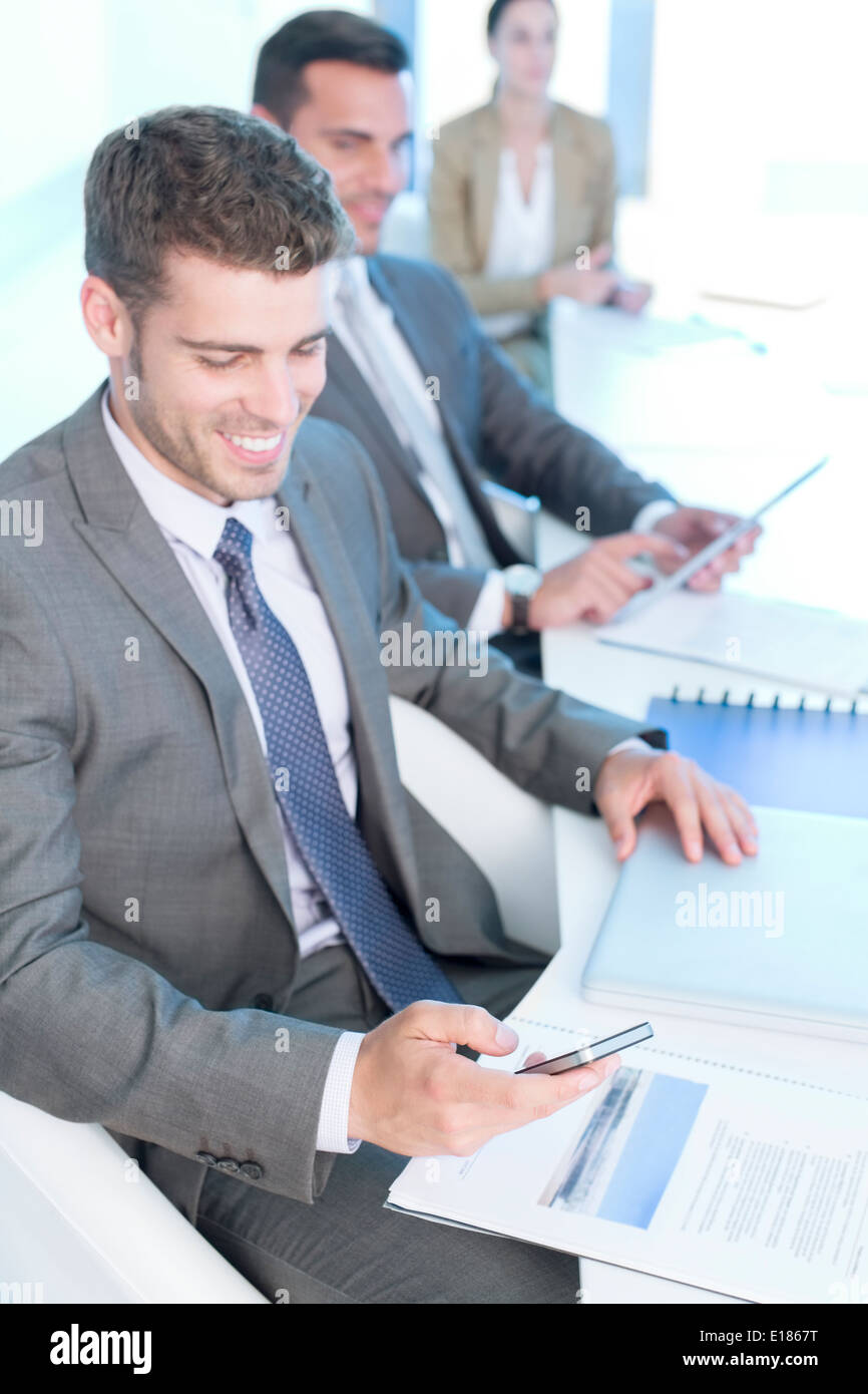 Businessman texting with cell phone in conference room Banque D'Images