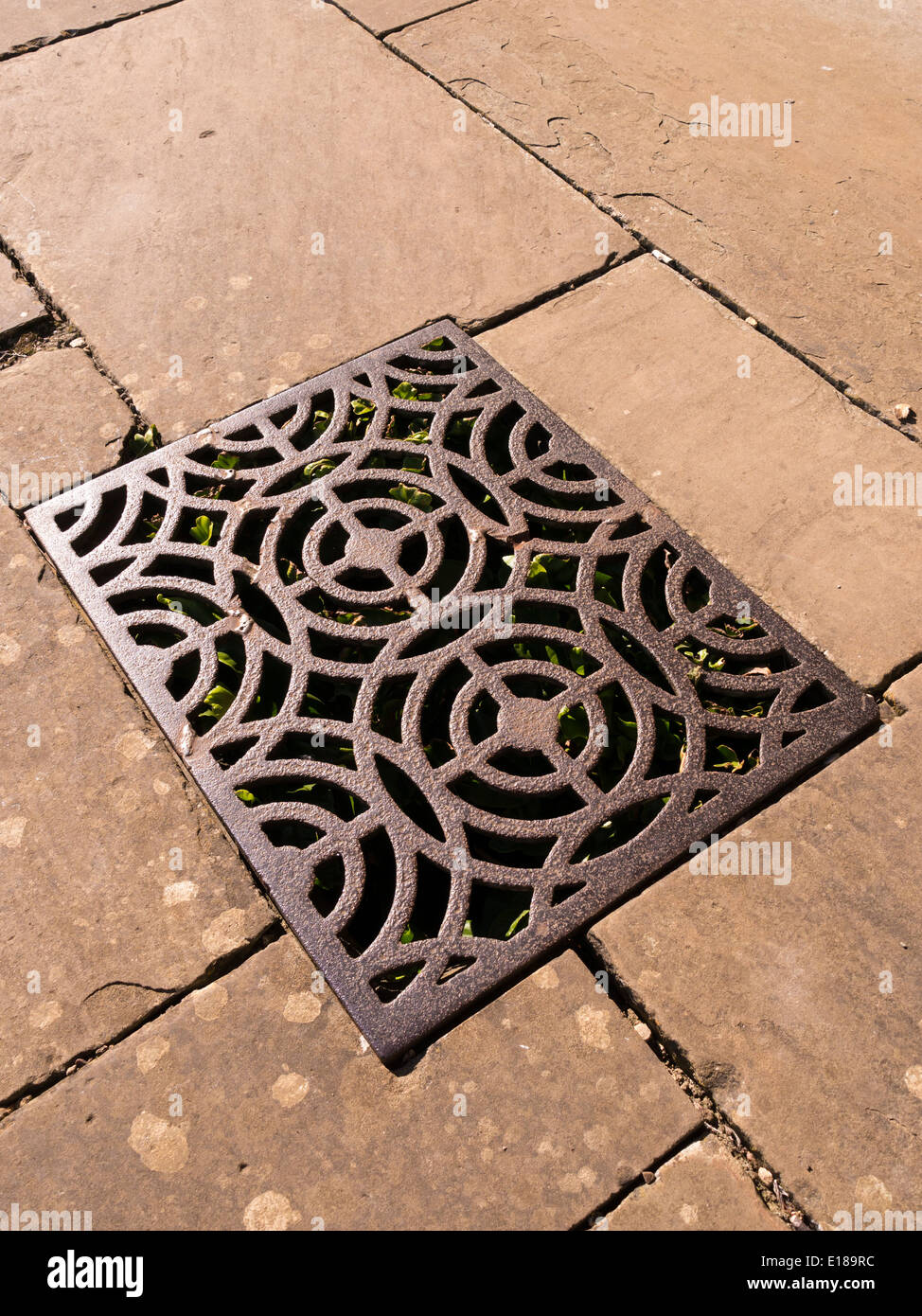 Fonte ouvragée éclairée par le drainage ou la grille de ventilation en métal fixé entre les dalles Banque D'Images