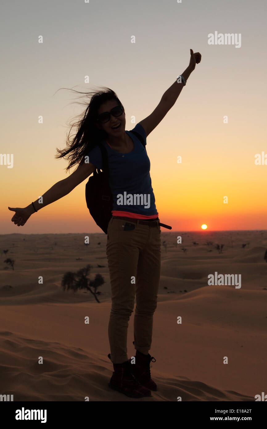 Une femme jouit d'un coucher du soleil dans le désert d'Abu Dhabi. Arbres stud le paysage aride. Banque D'Images