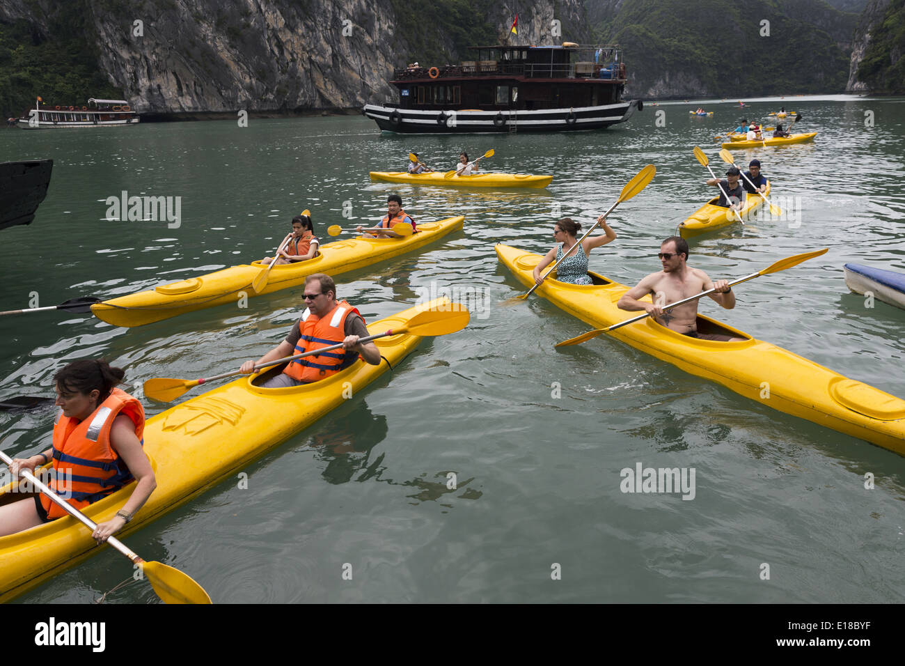 Un groupe de touristes utilisent des canoës pour naviguer entre les îlots de la Baie d'Ha Long Banque D'Images