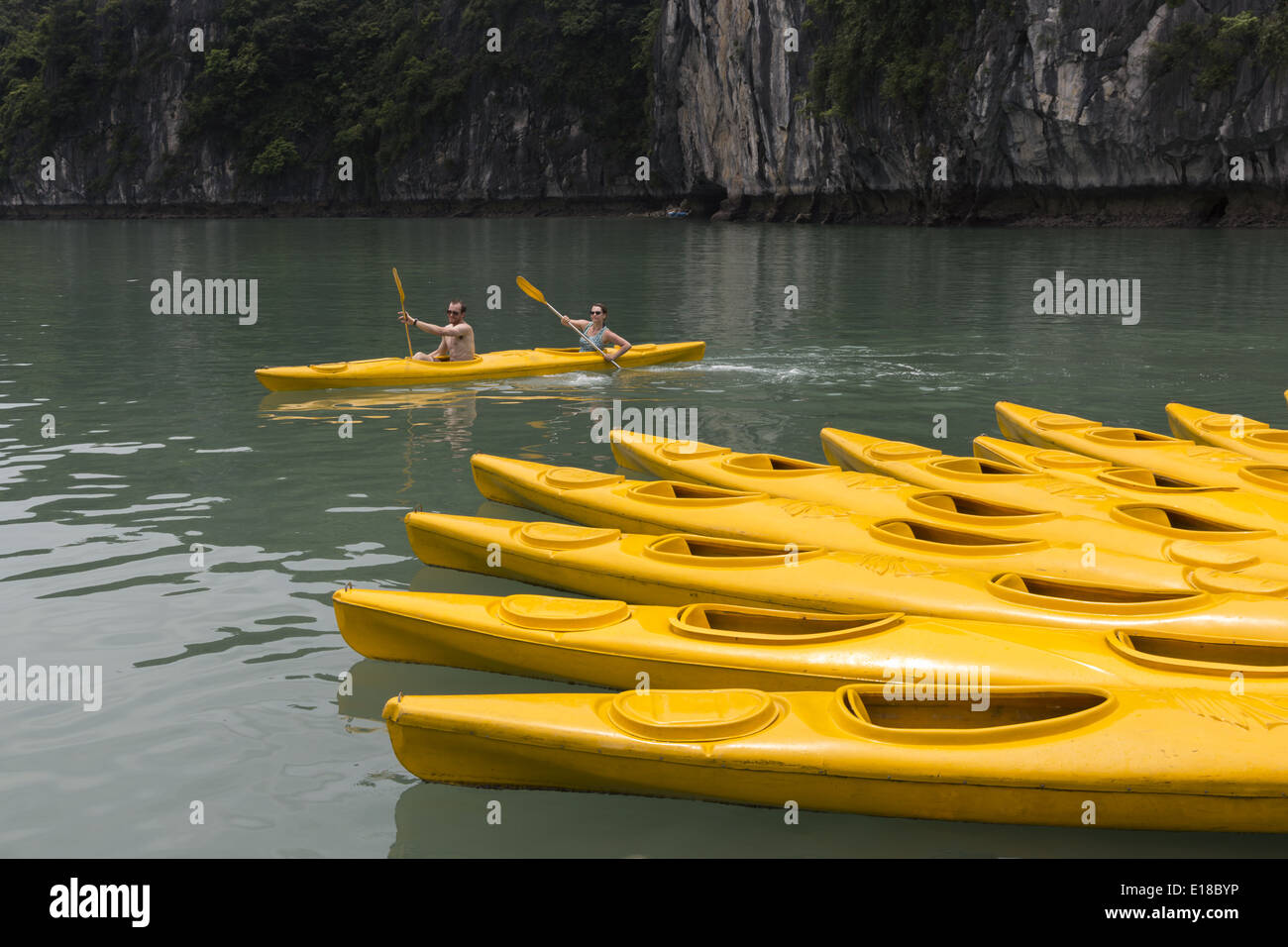 Un groupe de touristes utilisent des canoës pour naviguer entre les îlots de la Baie d'Ha Long Banque D'Images