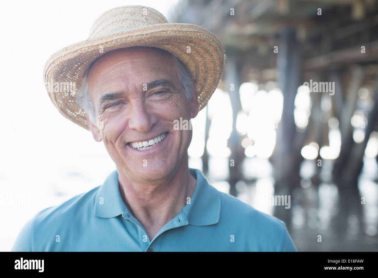 Portrait of smiling senior woman in sun hat at beach Banque D'Images