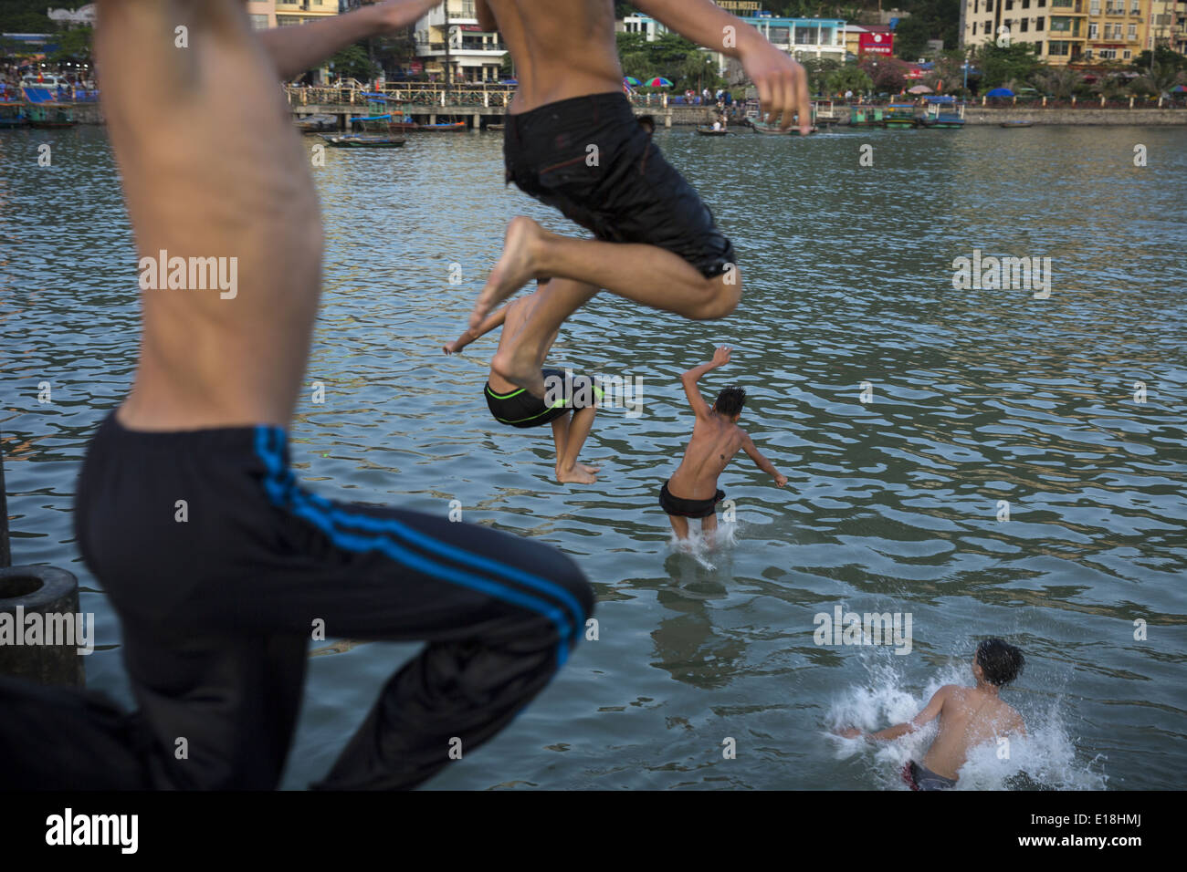 Un groupe de jeunes gens sautant dans l'eau de l'une des jetées, sur l'île de Cat Ba Banque D'Images