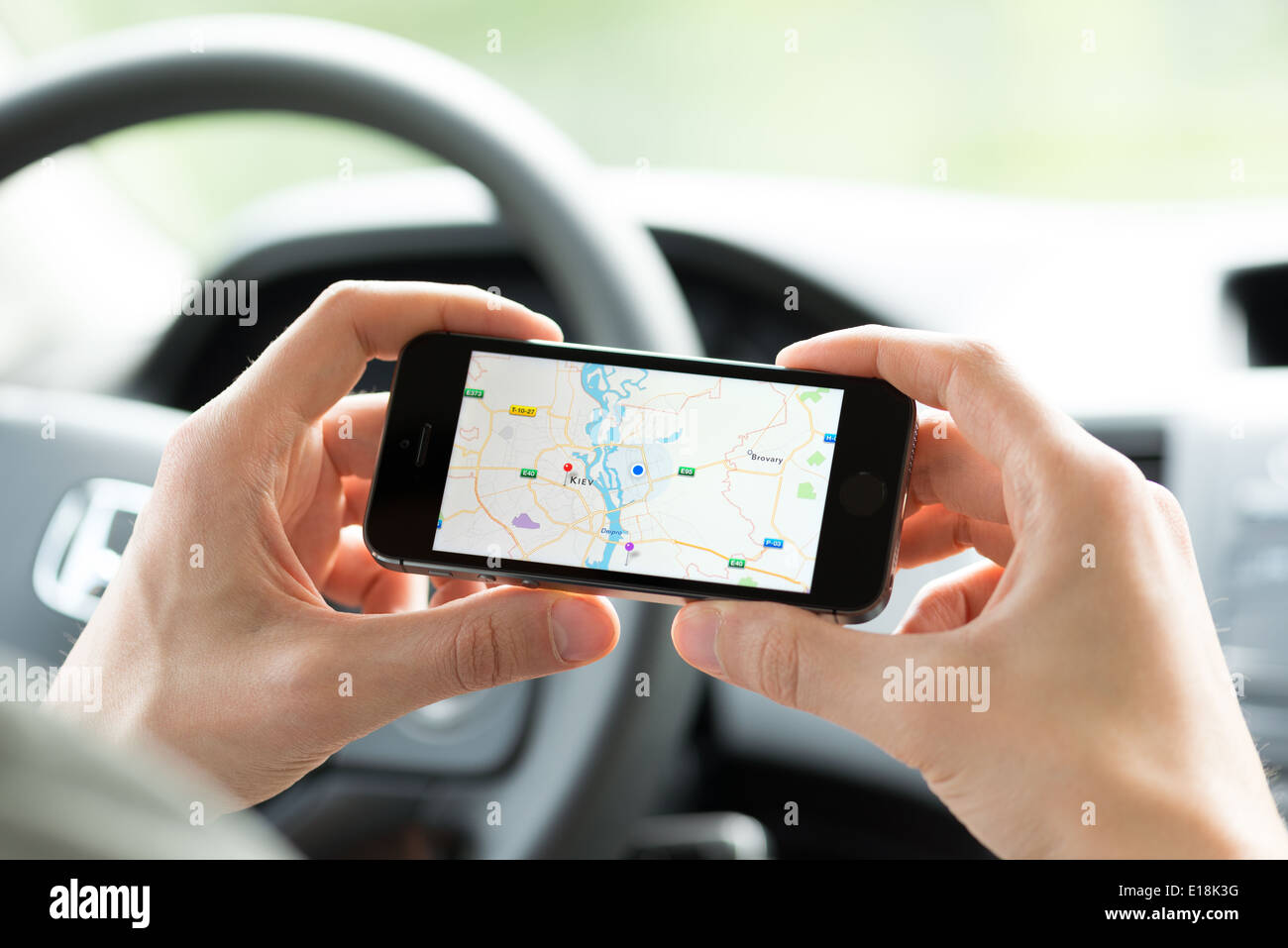 Homme dans la voiture de la planification d'un itinéraire à l'aide d'une application Google Maps sur Apple iPhone 5S Banque D'Images