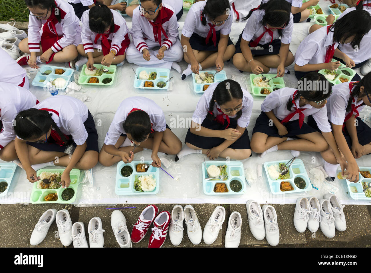 Les enfants de l'école s'asseoir pour manger après un concours des défilés. Banque D'Images
