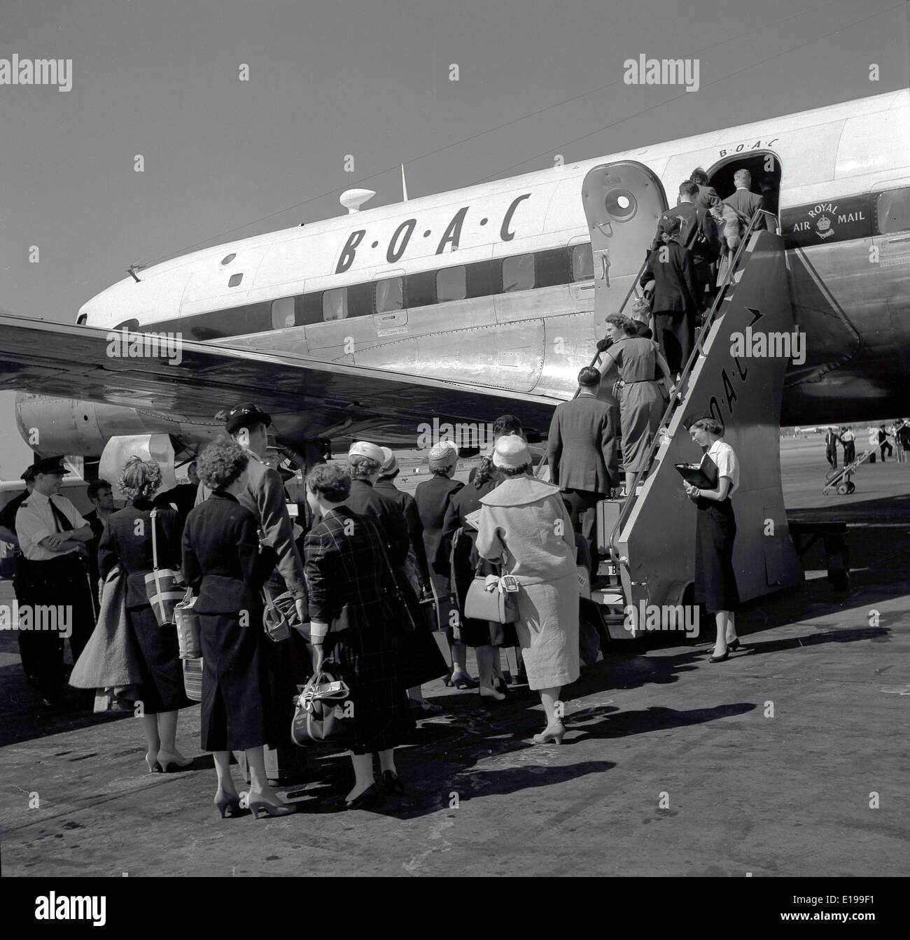 Historique Années 1950 Photo d'un groupe d'embarquement des passagers bien habillé les étapes sur un avion ne B.O.A.C encadré par une hôtesse de l'air Banque D'Images