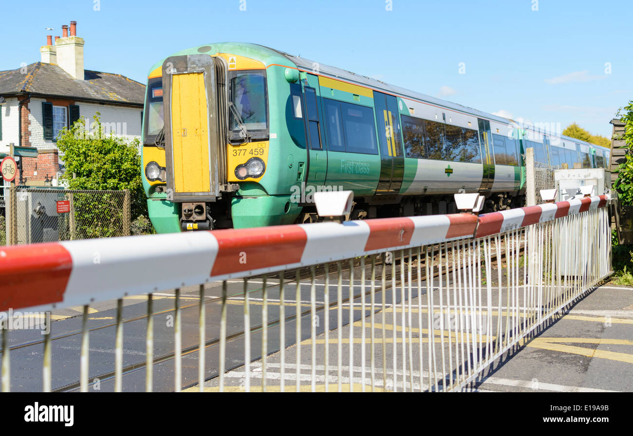 Train vert et jaune de classe 377 Electrostar Southern traversant un passage à niveau en Angleterre, au Royaume-Uni. Train du sud. Southern Rail. Banque D'Images