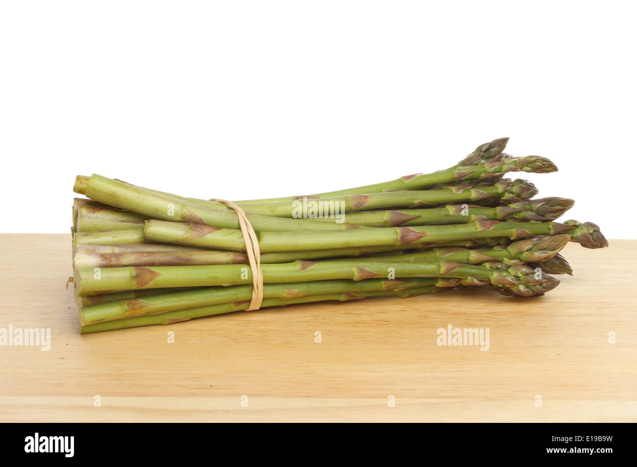 Ensemble d'asperges sur une planche en bois sur un fond blanc. Banque D'Images