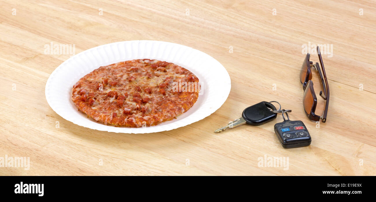 Une petite pizza au pepperoni, micro-ondes sur une assiette en carton avec  des clés de voiture et lunettes teintées sur le côté en haut d'une table à  manger Photo Stock - Alamy