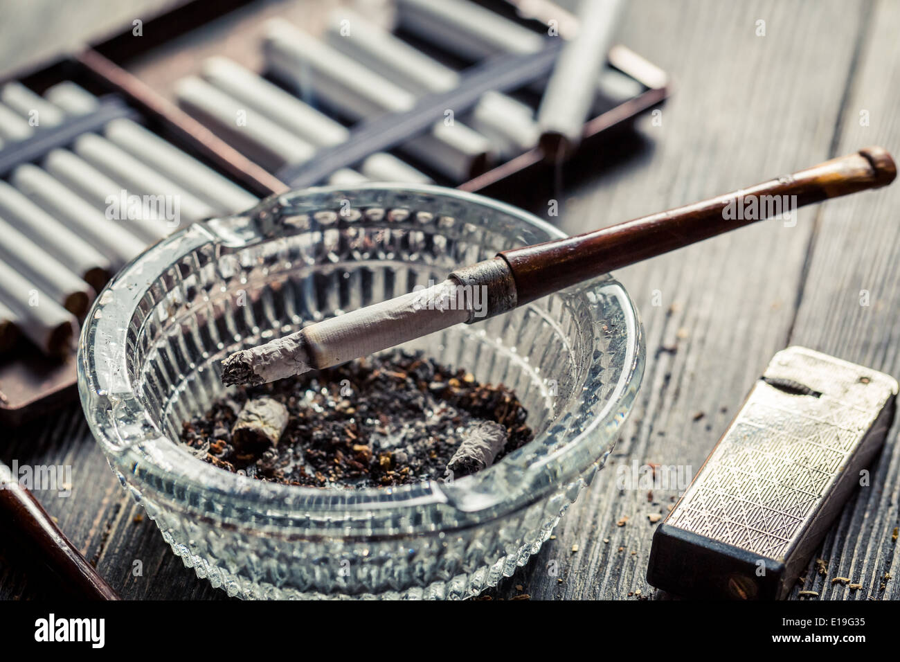 Cendrier en verre avec des tuyaux en bois, des cigarettes et plus léger autour de Banque D'Images