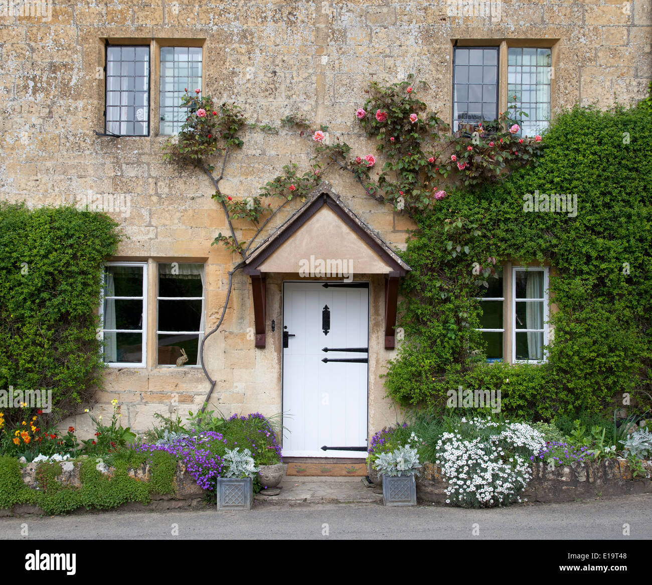 Pretty Cotswold cottage avec bordure à floraison printanière, Stanton, Gloucestershire, Angleterre. Banque D'Images