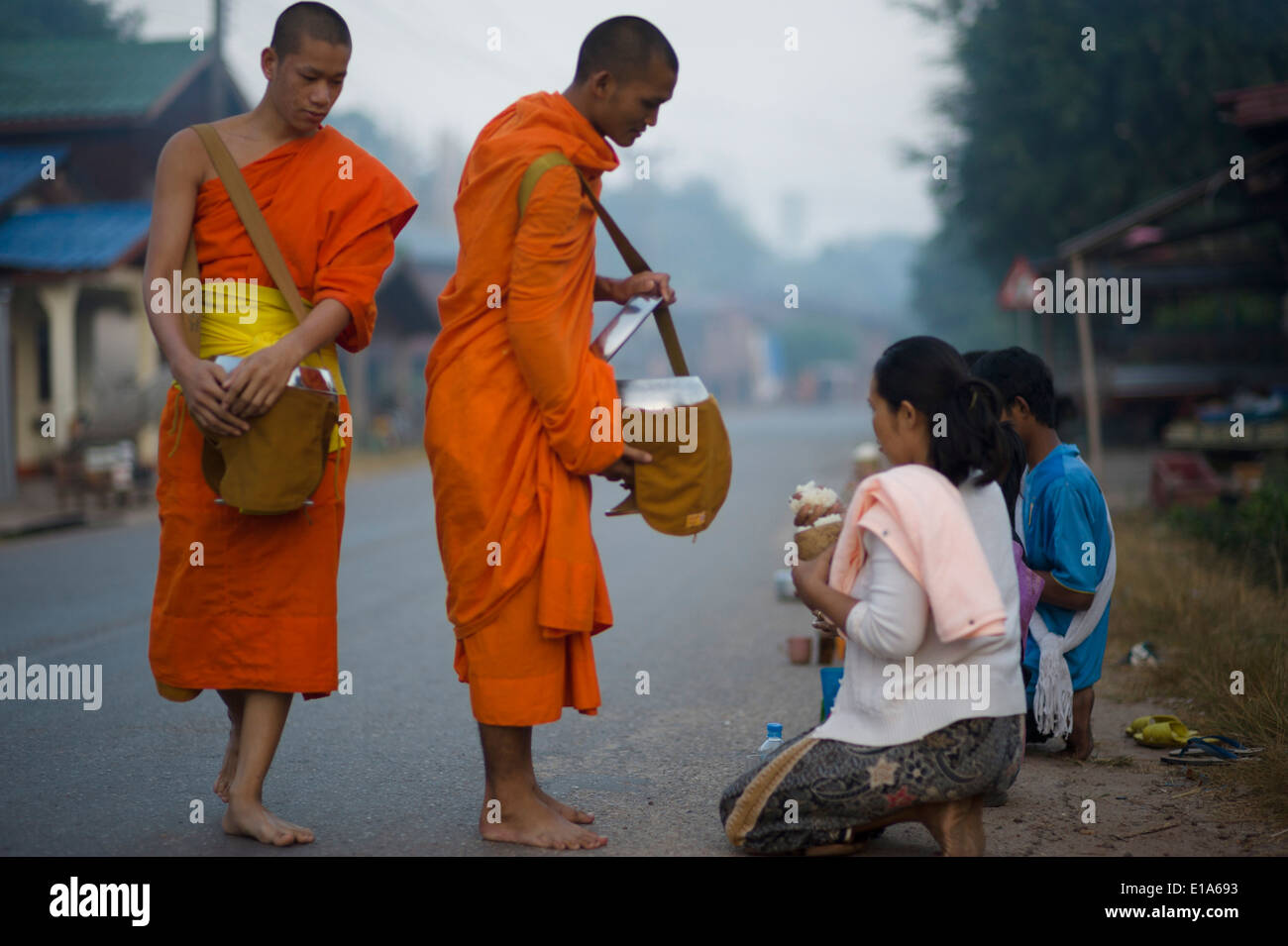 Les moines de Pha Sikhottabong, la collecte de l'aumône au lever du soleil, les villageois de Tha Kaek, Laos. Banque D'Images