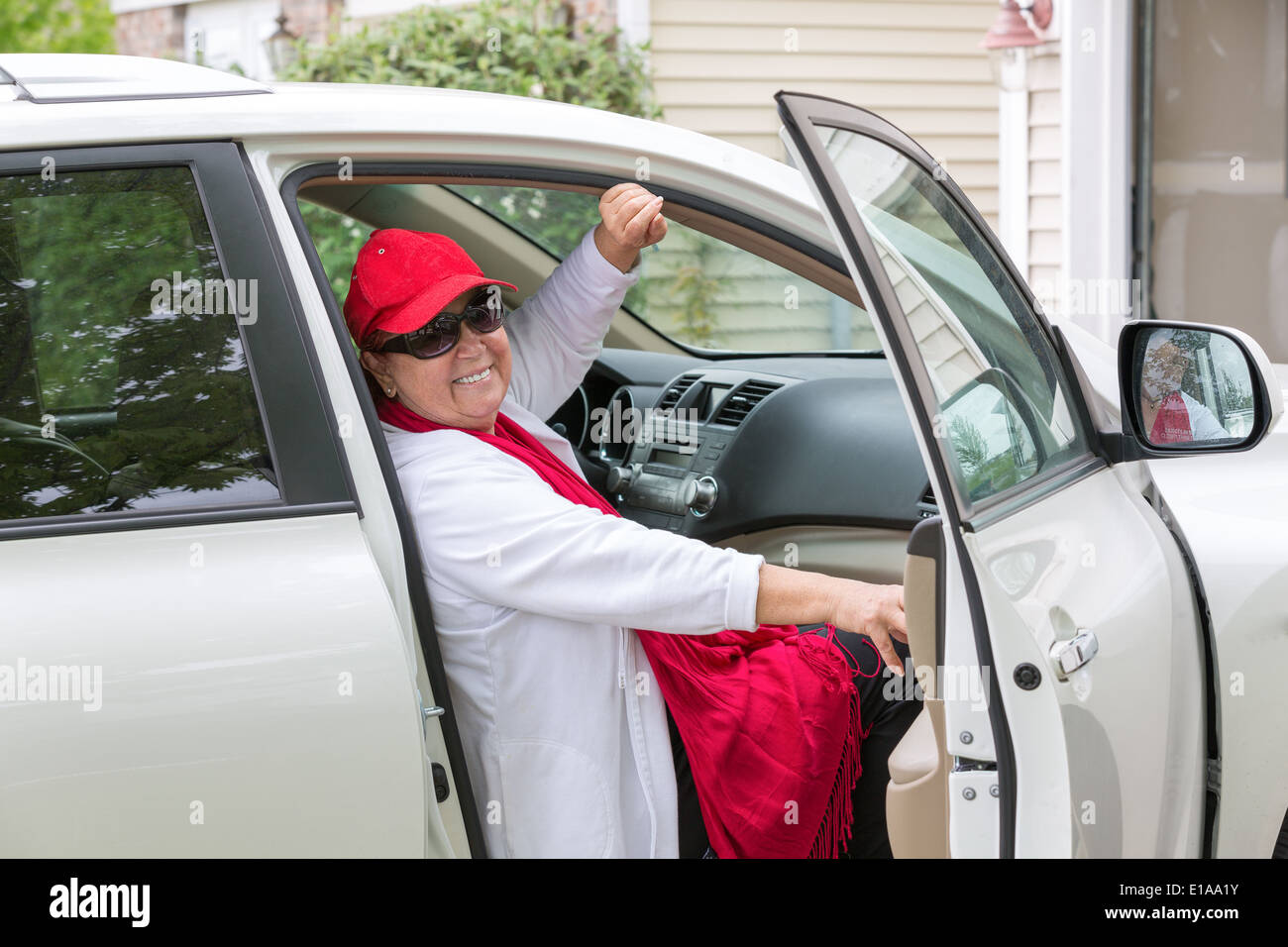 Senior lady avec red hat assis sur le siège passager se préparer fermer la porte et de prendre la route, elle a un véritable sourire sur h Banque D'Images