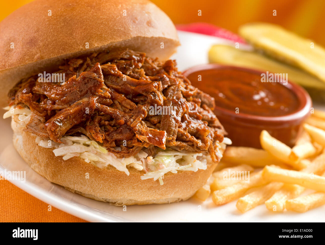 Un délicieux sandwich au porc avec de l'épaule de porc grillées, salade de chou, pommes frites, sauce, et les cornichons. Banque D'Images