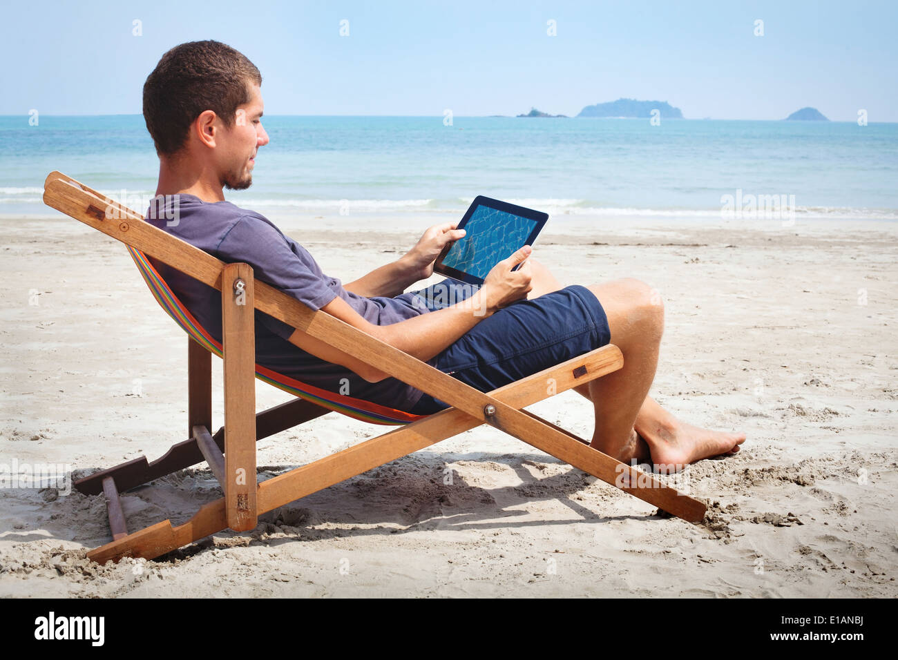 L'homme d'affaires travaillant avec tablette sur la plage Banque D'Images