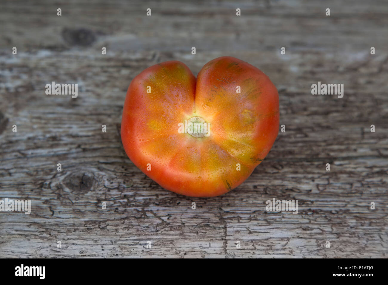 En forme de cœur unique tomate raf sur planche de bois rustique Banque D'Images