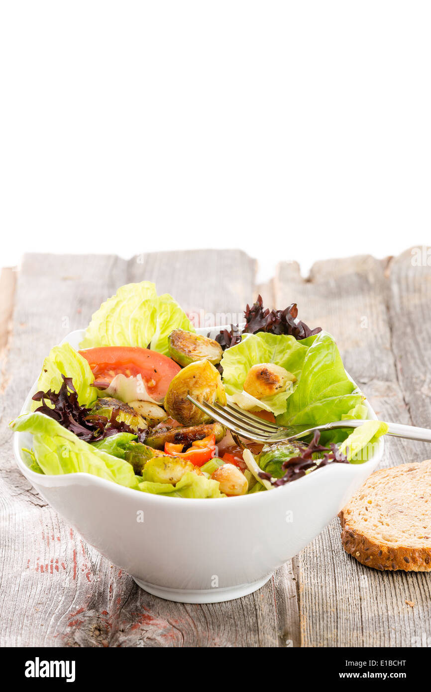 Salade végétarienne saine avec les choux de bruxelles sautés dans un mélange de légumes verts à salade avec tomate et radis servi sur un vieux grun Banque D'Images
