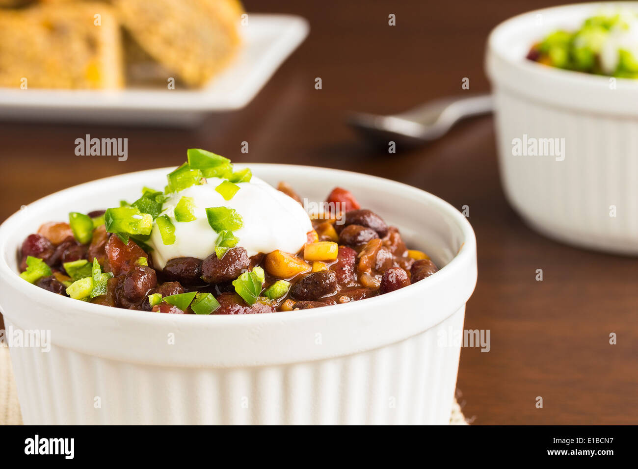 Chili végétarien avec oignons, tomates, maïs, haricots noirs et des reins, garnie de crème sure et de dés de jalapeno, avec cornbread Banque D'Images