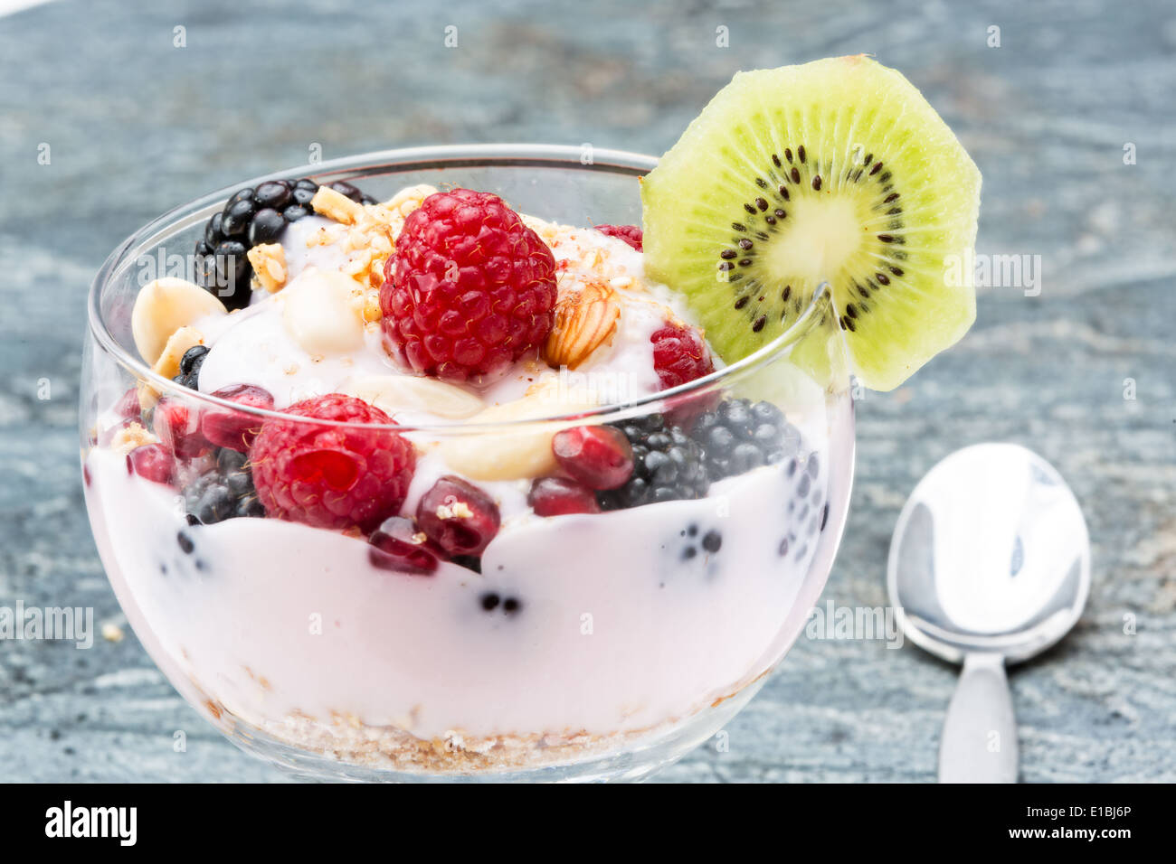 Libre d'un verre de délicieux petits fruits congelés contenant parfait, graines de grenade framboises mûres et amandes, garnishe Banque D'Images