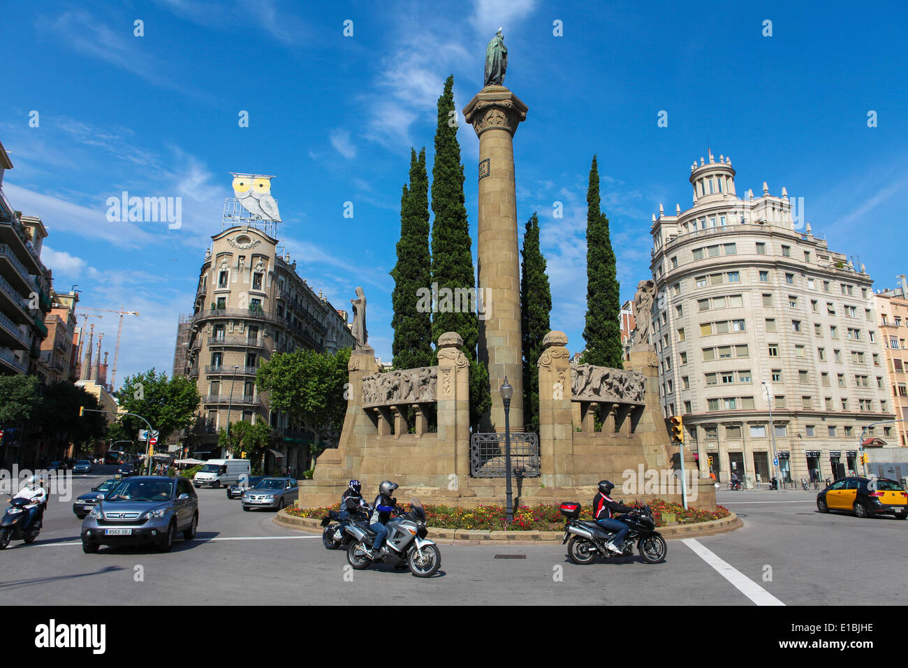 Des personnes non identifiées dans le trafic près de Roura Rótulos Company Construction (avec le hibou) et une statue dans le centre de Barcelone. Banque D'Images