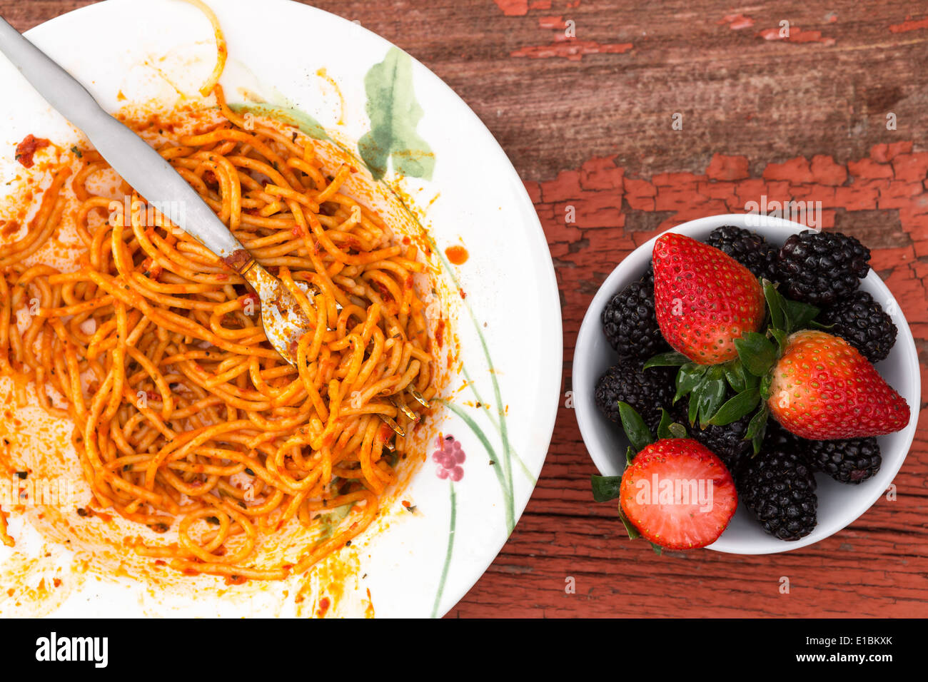 Vue aérienne d'un plat de spaghettis à la bolognaise dans une riche sauce tomate et dessert aux petits fruits avec des fraises et noir Banque D'Images