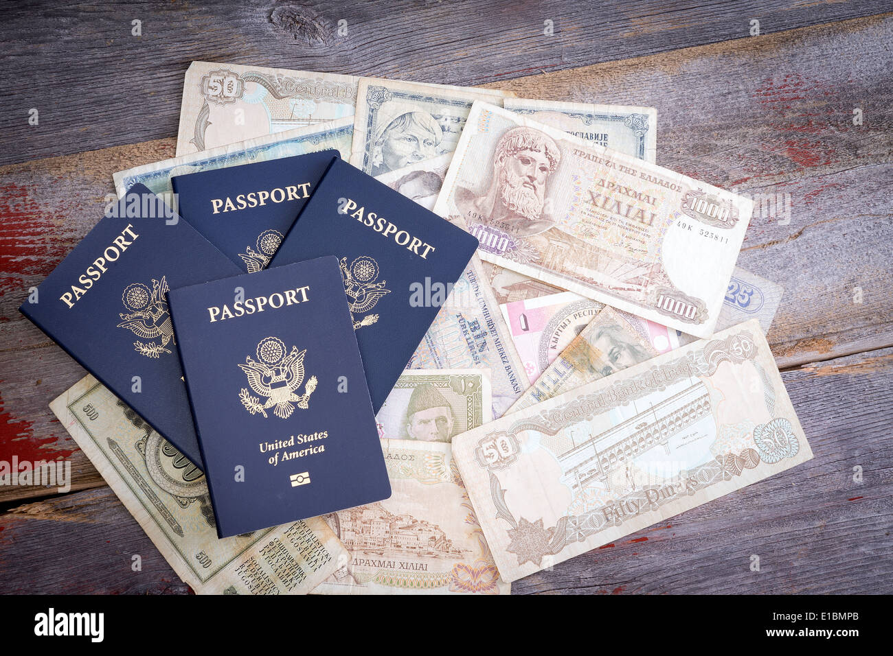 Groupe de quatre un passeport américain avec des billets étrangers dans différentes devises allongé sur une table en bois représentant la planification et f Banque D'Images