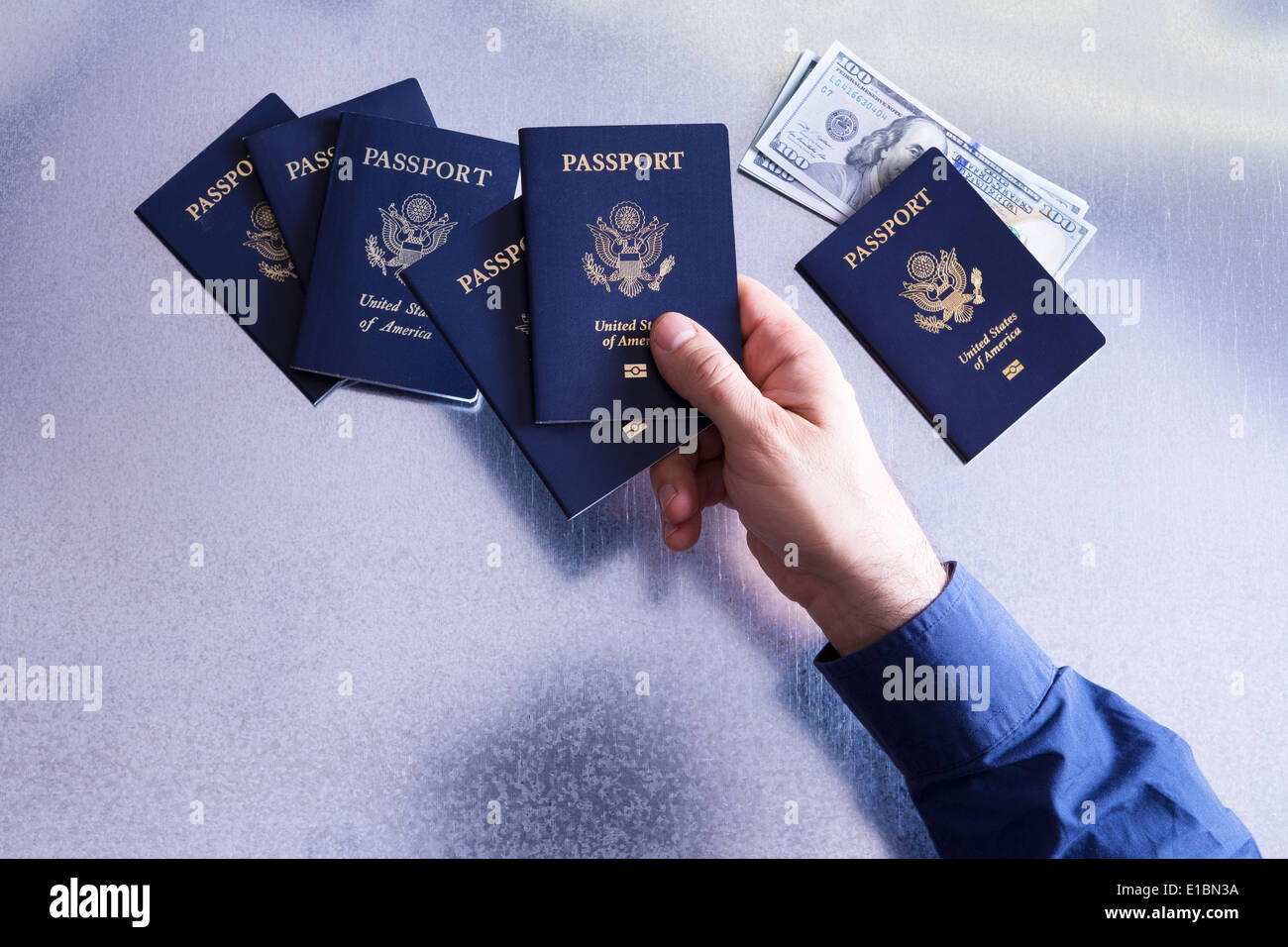 Vue de dessus de la main d'un homme le tri et contrôle de passeports américains avec des dollars dans l'un représentant un homme de famille, Banque D'Images
