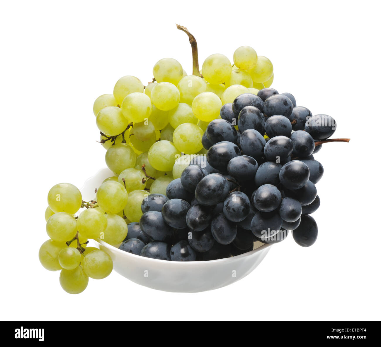 Grappes de raisin noir et vert dans une tasse blanche sur fond blanc, isolé Banque D'Images