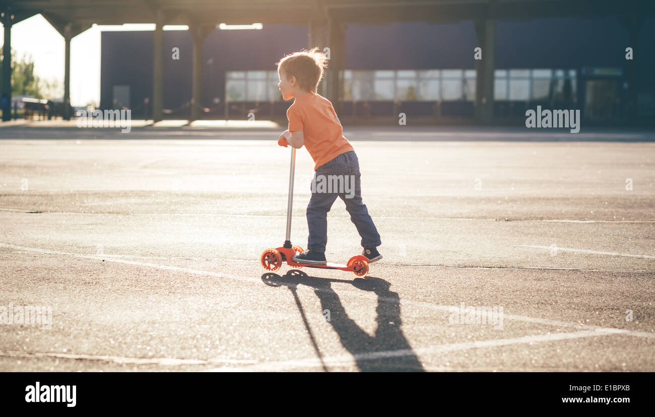 Peu de beau garçon un scooter Banque D'Images