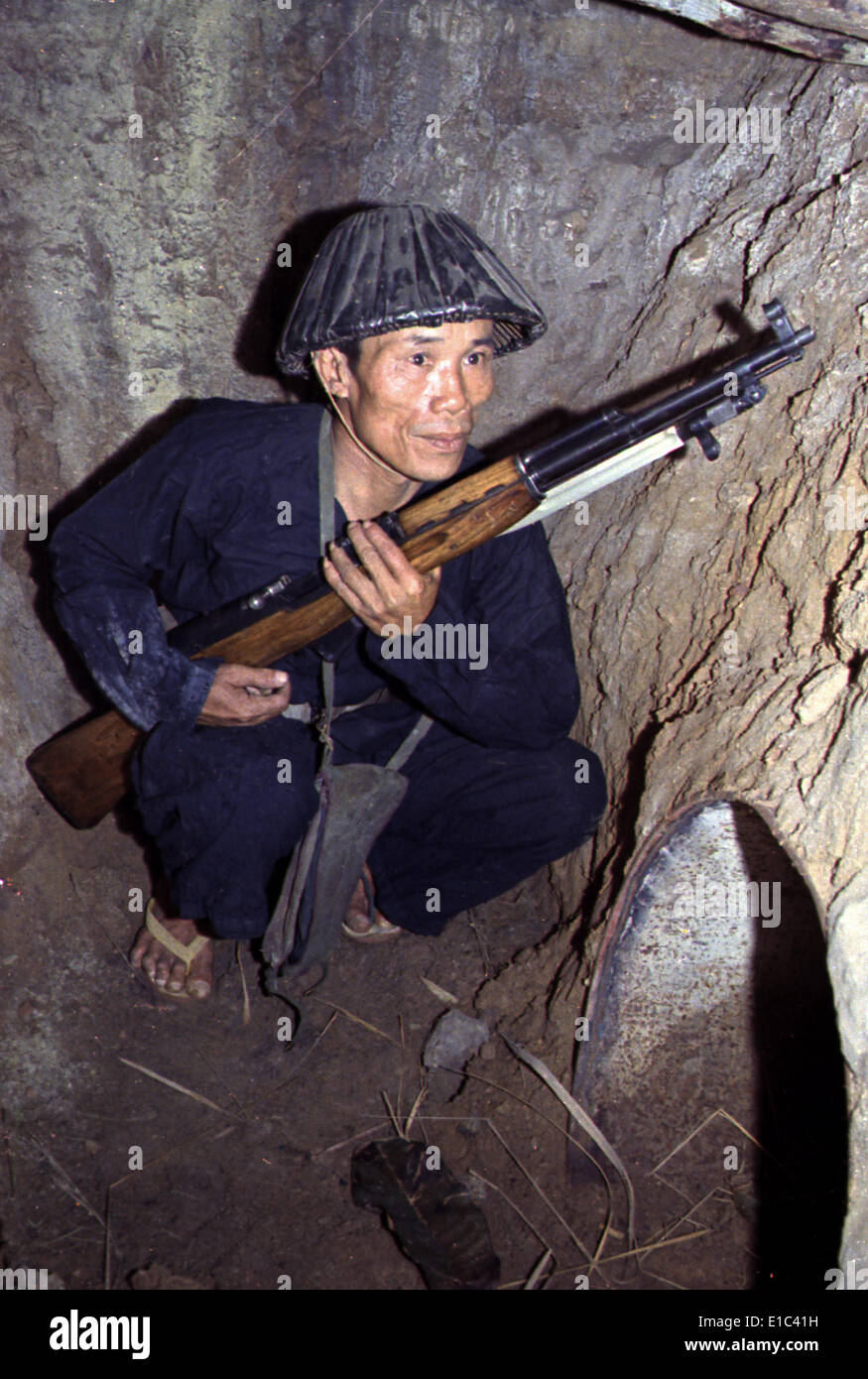 Guerre du Vietnam, un soldat Viet Cong, s'accroupit dans un bunker avec un fusil SKS, fin des années 1960 Banque D'Images