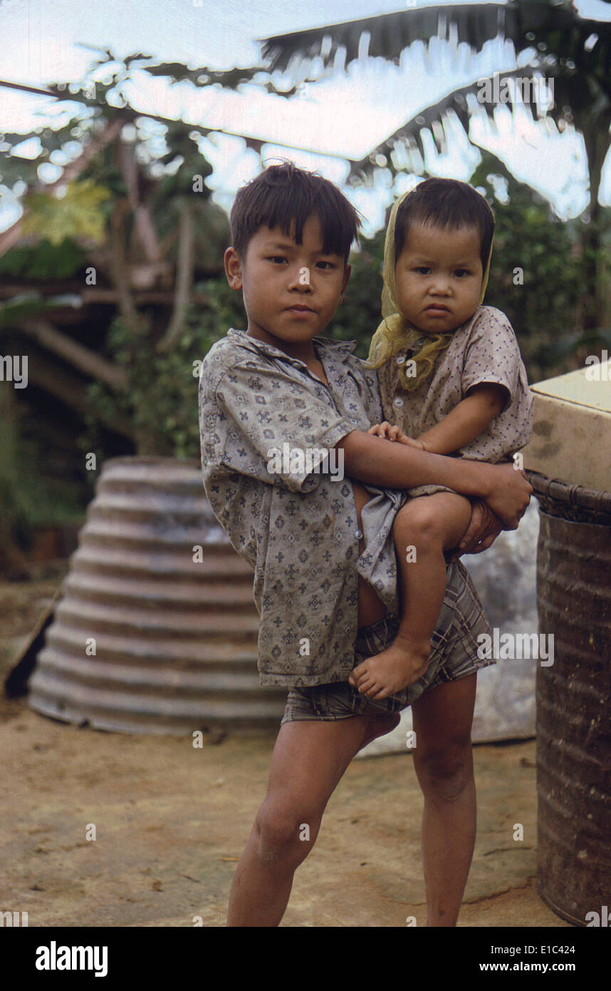 Guerre du Vietnam, le Camp de Phu Bai, Campbell, la République du Vietnam. Un garçon vietnamien porte un jeune enfant, fin des années 1960 Banque D'Images